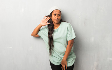 Young afro american woman on textured background listening to something by putting hand on the ear