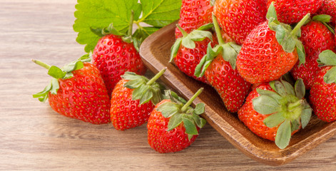 A plate of beautiful strawberries isolated on wooden background, close up, macro.