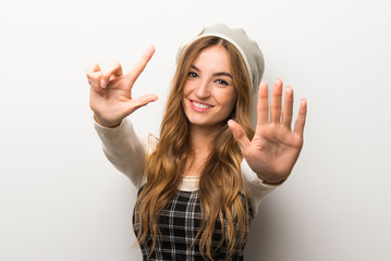 Fashionably woman wearing hat counting seven with fingers