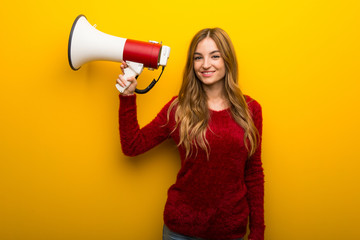 Young girl on vibrant yellow background holding a megaphone