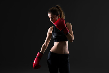 Sport woman with boxing gloves on dark background