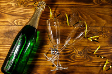 Champagne bottle and two empty champagne glasses on wooden background. Top view