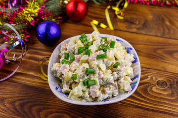 Traditional Russian festive salad Olivier and New Years decorations on wooden table
