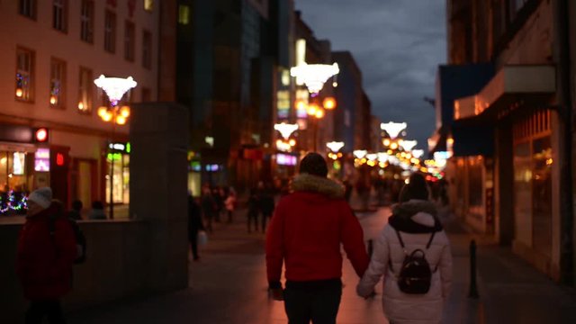 Young Man and Woman Lovers walking along the Night Christmas Street in the City