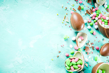 Fototapeta na wymiar Colorful spring easter sweets background, with chocolate eggs, sugar sprinkles and marshmallow bunny, turquoise light blue concrete background copy space top view