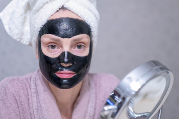 Young girl in a cleansing black coal mask on her face. Black coal exfoliating mask for the face....