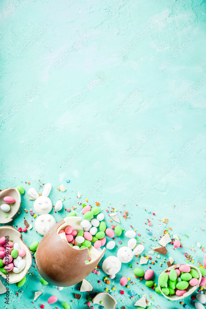 Wall mural Colorful spring easter sweets background, with chocolate eggs, sugar sprinkles and marshmallow bunny, turquoise light blue concrete background copy space top view