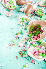 Colorful spring easter sweets background, with chocolate eggs, sugar sprinkles and marshmallow bunny, turquoise light blue concrete background copy space top view