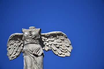 An old andstone sculpture of a headless angel. 