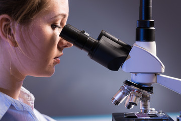 beautiful science student looking into a microscope in a laboratory