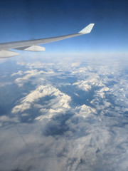 Fototapeta premium Clouds, mountains and plane wing from plane window