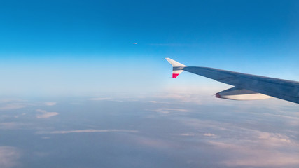 Wing of an airplane flying above the morning clouds