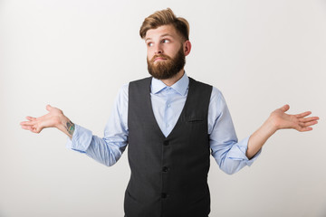 Confused young bearded man standing isolated over white wall background.