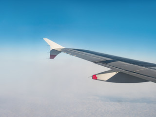 Wing of an airplane flying above the morning clouds