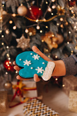 Female hand holding glazed cookie shaped as blue mitten