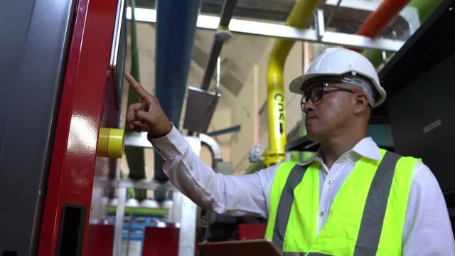 Asian engineer wearing glasses working in the boiler room,maintenance checking technical data of heating system equipment,Thailand people	