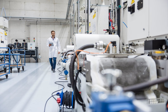 Employee Checking Manufacturing Machines In High Tech Company, Using Digital Tablet