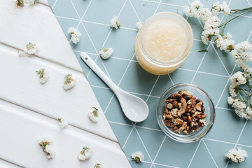 Walnuts, honey and white flowers on table