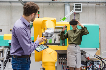 Colleagues in high tech company testing new technologies, using digital tablet and VR goggles