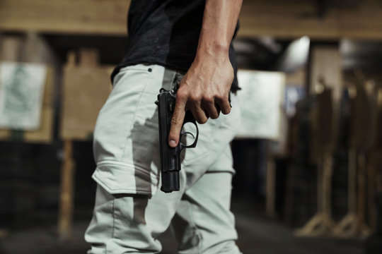 Close-up of man holding a pistol in an indoor shooting range