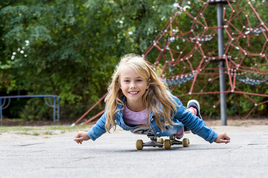 Portrait of smiling blond girl with skateboard on a playground