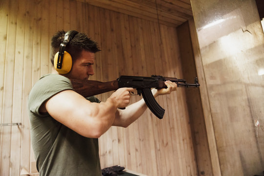 Man aiming with a rifle in an indoor shooting range