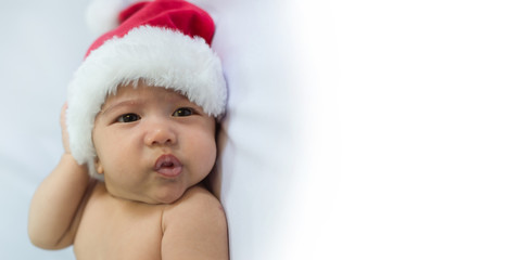 little baby with Santa Claus hat poses for a photo shoot. concept of celebrates Christmas and New Year's holidays and copy space for text.