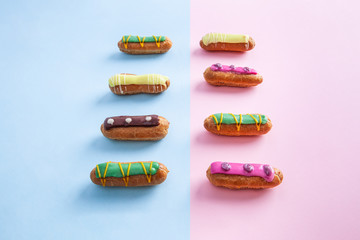 Decorated colorful eclairs on pink and blue divided background