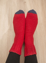A woman wearing warm hand craft socks. Knitted from a natural sheep wool yarn. Winter clothing. On a wooden background.