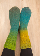 A woman wearing warm hand craft socks. Knitted from a natural sheep wool yarn. Winter clothing. On a wooden background.