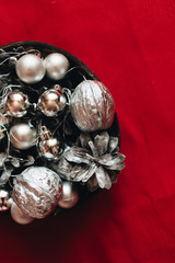 Christmas decoration with silver balls, baubles and pine cones on red background