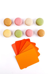 Colorful French macarons with color swatches in red orange hues. Top view with copy space
