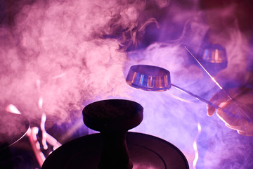 A man's hand holds the lid off the hookah.