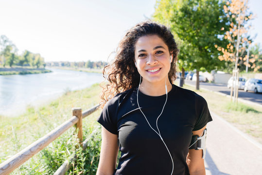 Portrait of smiling sportive young woman at the riverside