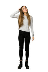 Full-length shot of young girl thinking an idea while scratching head on isolated white background