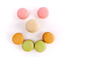 Obraz na płótnie Canvas Colorful macarons arranged in a shape of smiley face isolated on white with copy space