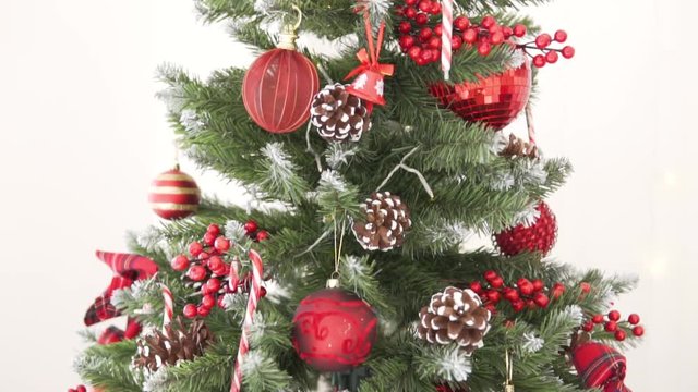 Large stylishly dressed Christmas tree. Slow shooting of tree decorations from top to bottom. New Year Christmas. Classic red color gamut.