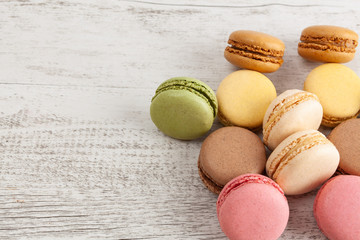 Pile of colorful French macarons on white rustic wooden table with copy space