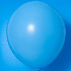 Blue balloon on blue background with shadow. Side glare.
