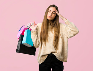 Young girl with shopping bags unhappy and frustrated with something on isolated pink background