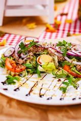 Salad with meat, egg, vegetables on white plate. Close up