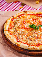Italian Pizza Margherita with tomatoes and mozzarella cheese on wooden cutting board. Close up
