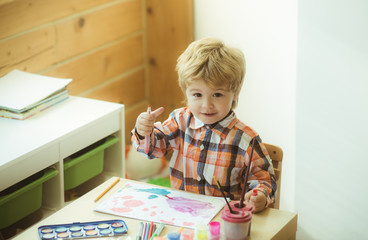 The boy draws a Christmas card. Drawing lessons. Creative development and education. Leisure time at home. Paint for painting. Cute boy is sitting at the children's table.