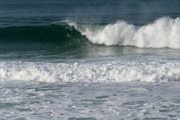 Atlantic wave and surfer, Nazare, Portugal.