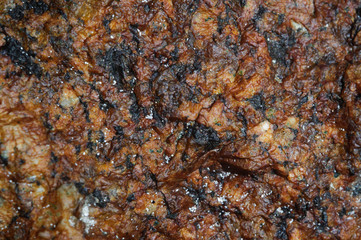 The surface of the brown rock with colored inclusions.