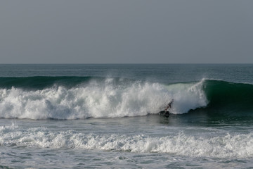 Atlantic wave and surfer, Nazare, Portugal.