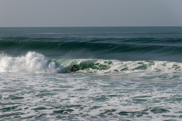Atlantic wave and surfer, Nazare, Portugal.