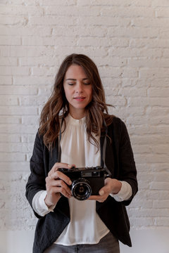 Beautiful woman with photo camera near brick wall
