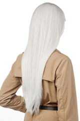 A back view side portrait of a lady with long white hairstyle, wearing a beige belted coat with long sleeves and epaulettes. The woman is posing on the white background. New-fashioned hairstyle. 