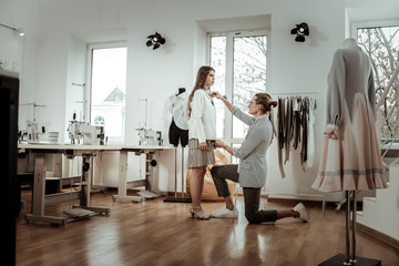 Fototapeta premium Pretty dark-haired model in a beige skirt working in a showroom